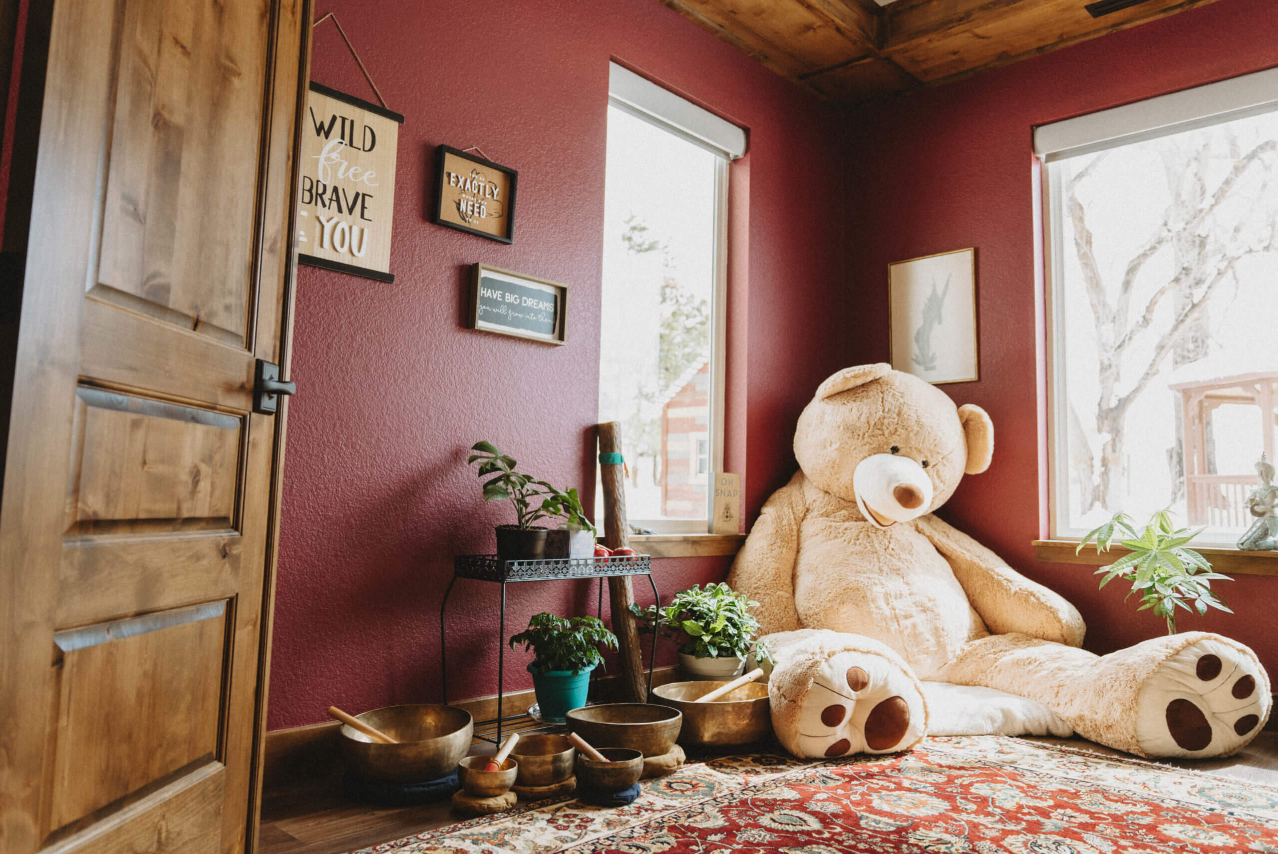 Gardens Spotlight: The Reflection Room Wide shot of a red room with bright windows and a giant stuffed teddy bear