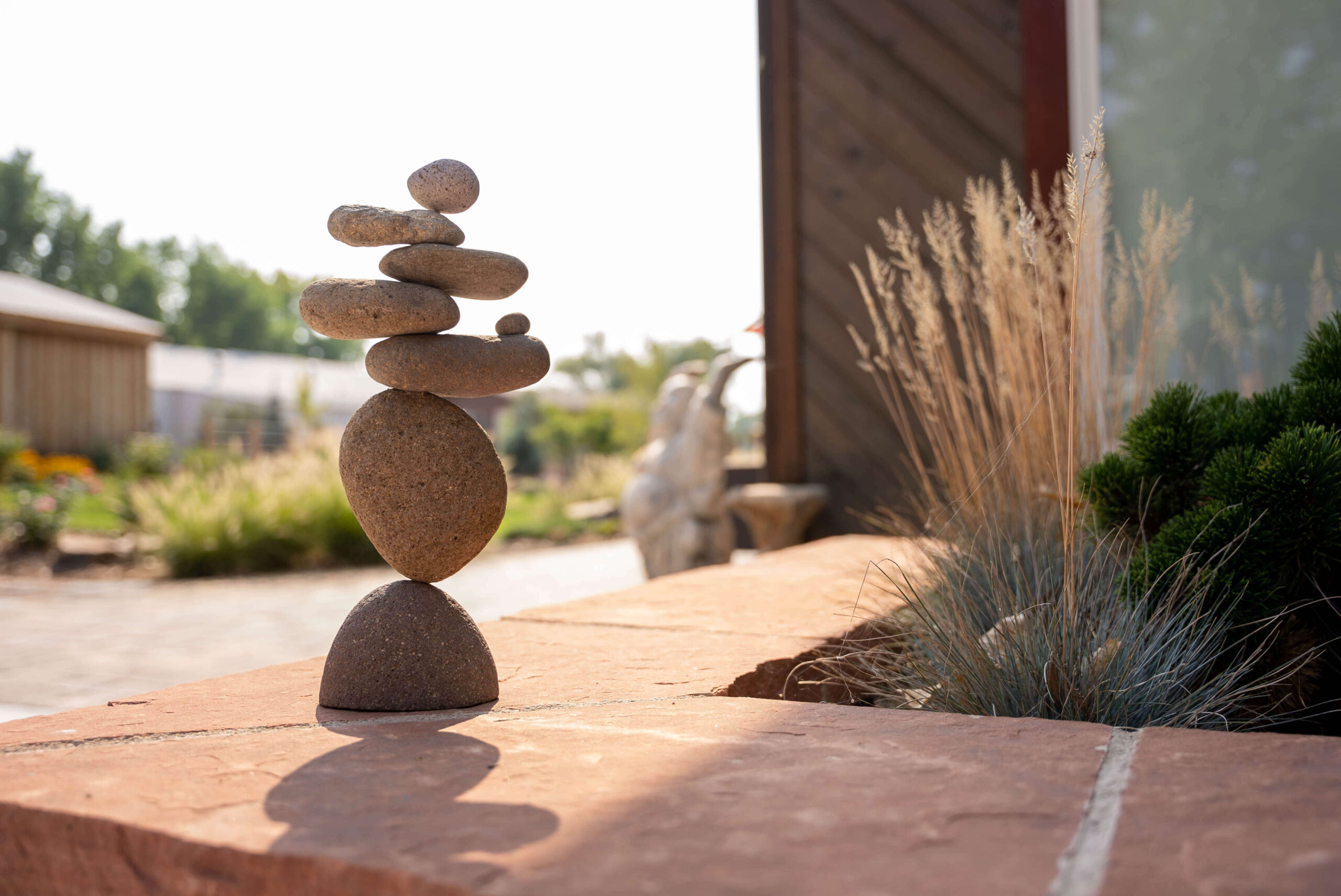 Eight rocks balancing on top of each other next to grass